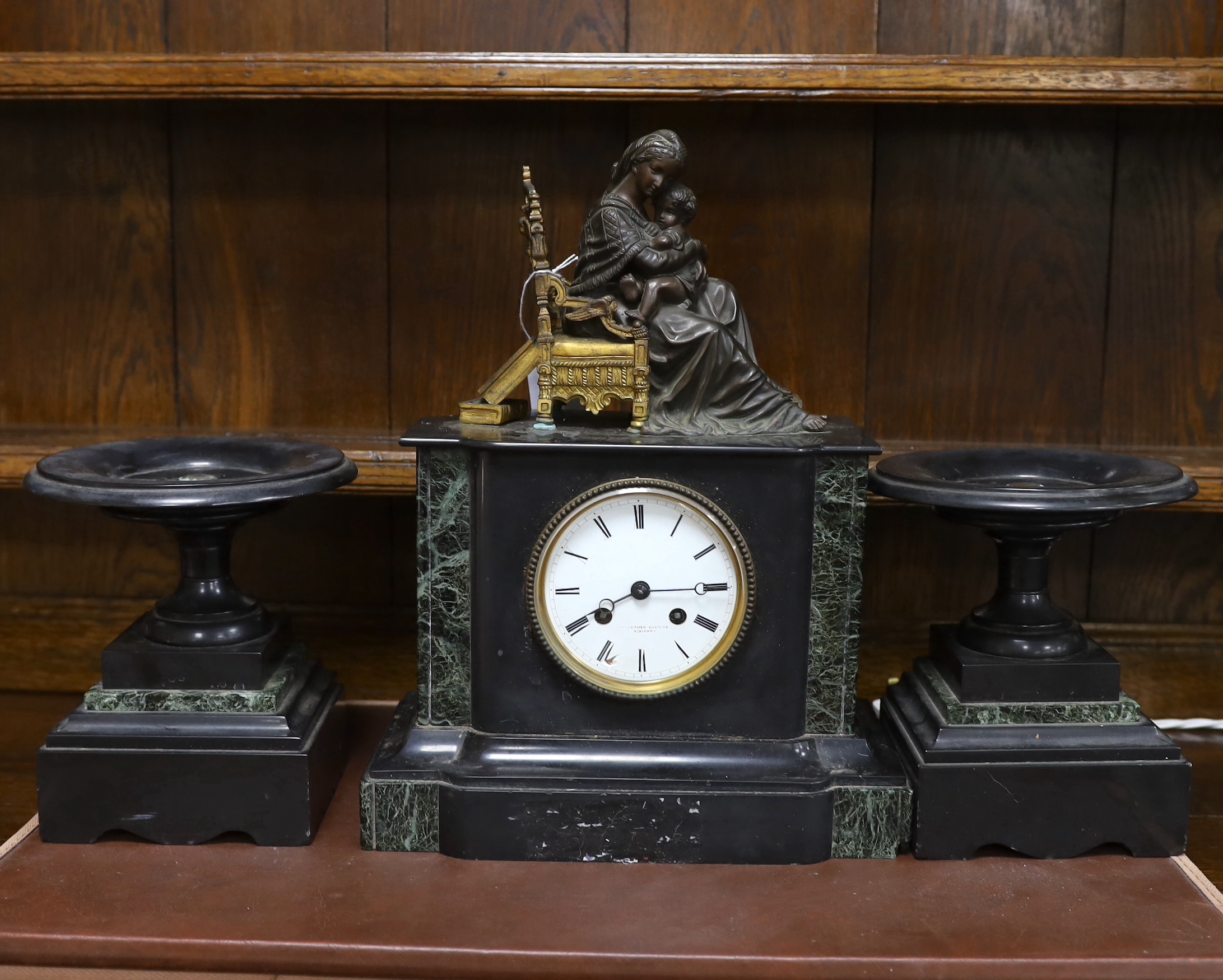 A late 19th century French black slate clock garniture with seated mother and child metal mount, clock 38cm high